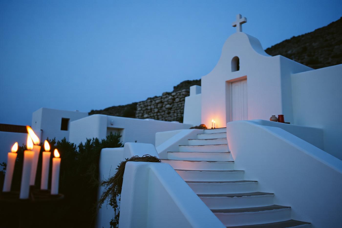 Candles on whitewashed chapel steps at dusk in a Greek village